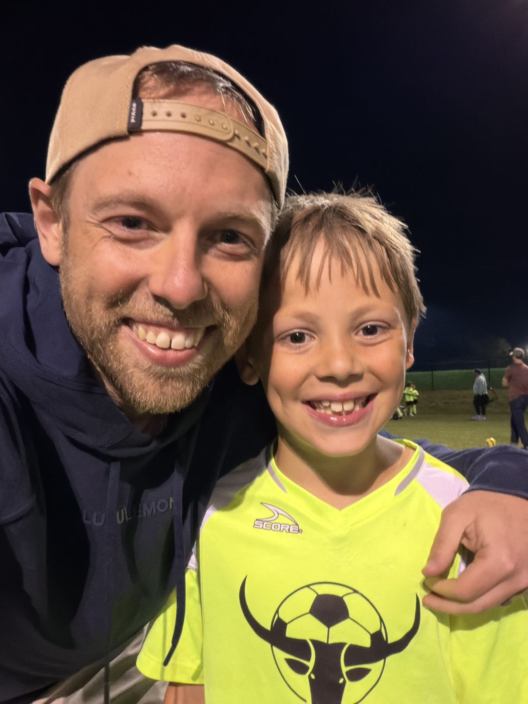 Aaron with his son on the soccer field at night