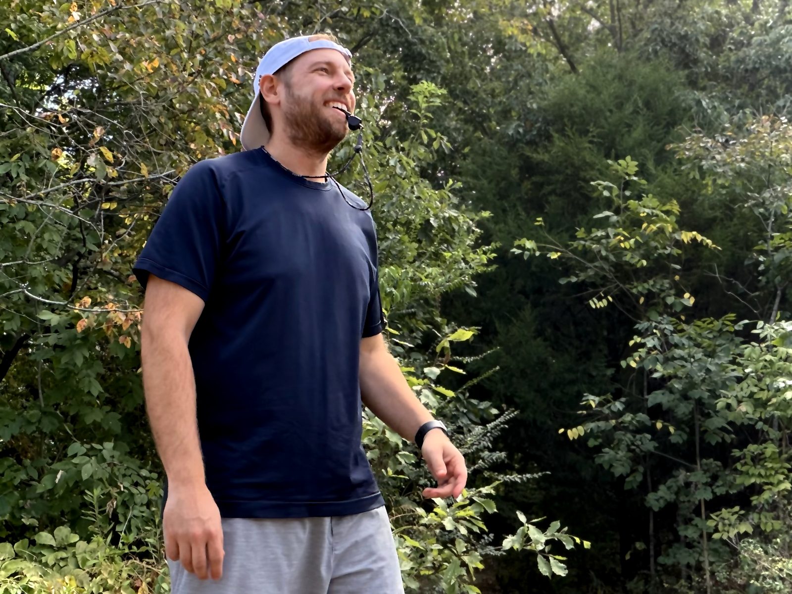 Aaron coaching flag football with a whistle in his mouth, smiling