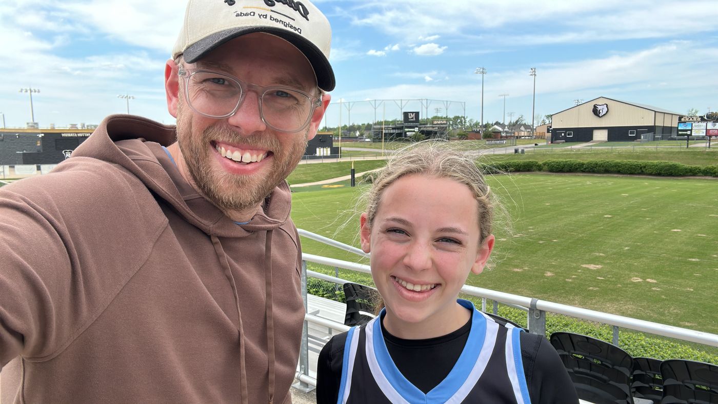 Aaron and his daughter in her jersey at a stadium