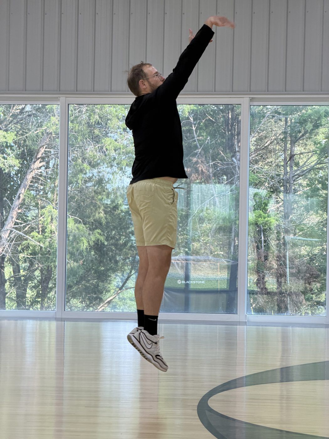 Aaron in mid-air taking a jump shot in a gym