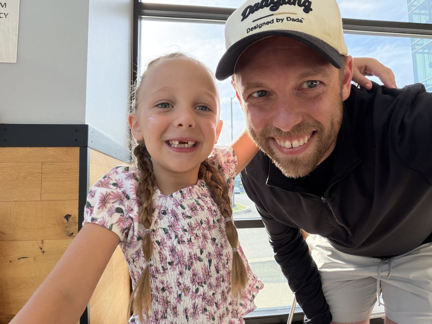 Aaron in a DadGang hat grinning with his youngest daughter