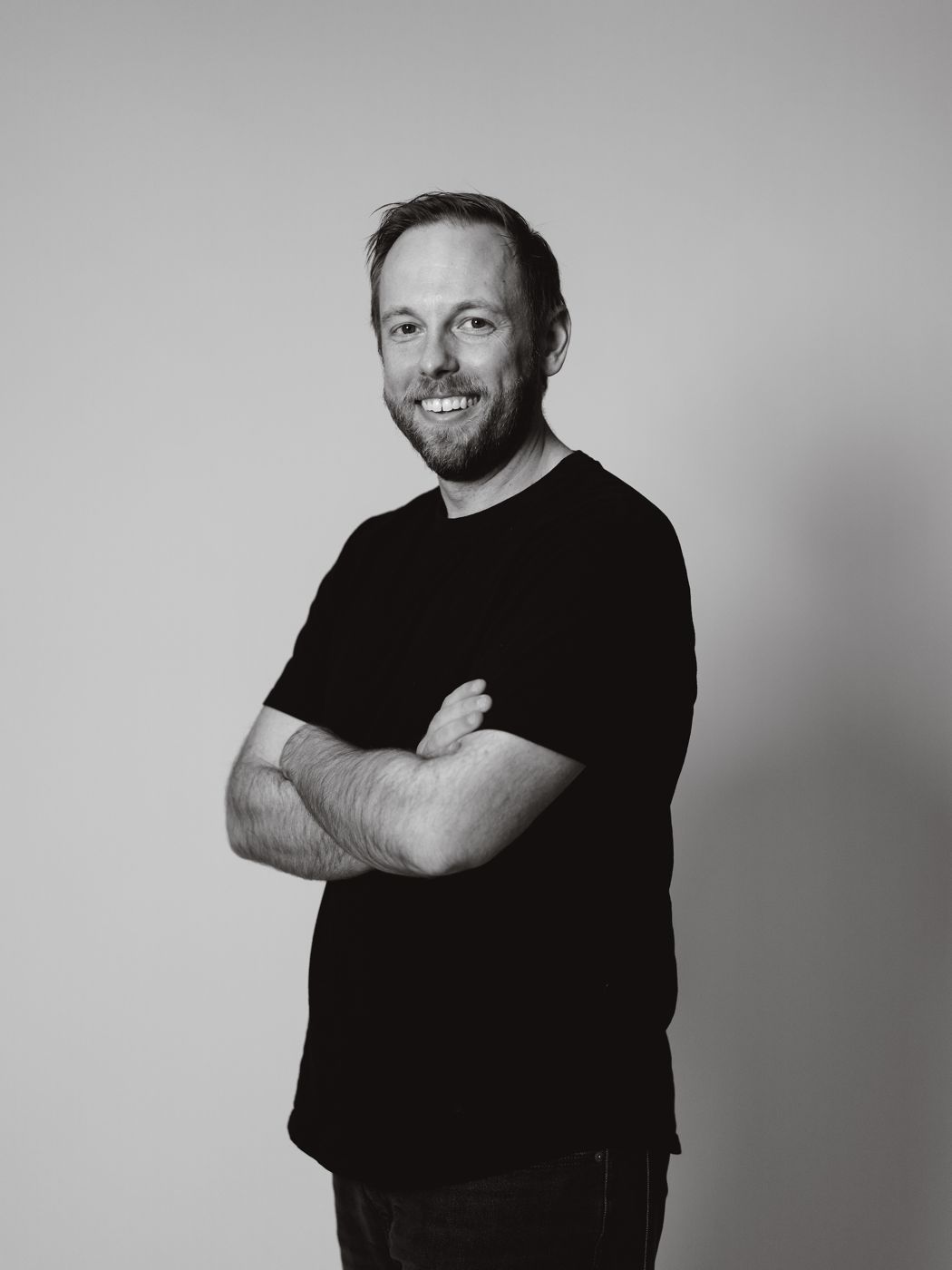 Black and white portrait of Aaron, arms crossed and smiling